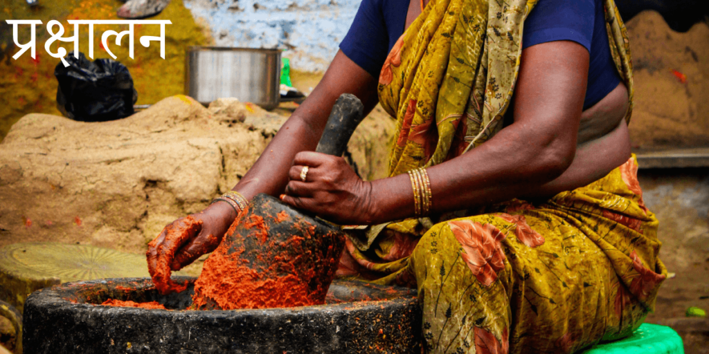 une femme écrasant des chillis rouges dans un mortier et un pilon massifs avec le titre sanskrit पथ्य - Pathya - Bénéfique