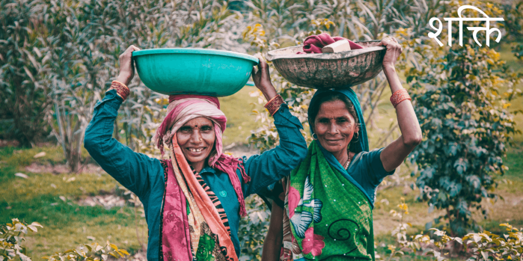 Deux femmes indiennes souriantes et radieuse assise entourée de nourriture avec le titre sanskrit शक्ति Shakti pouvoir